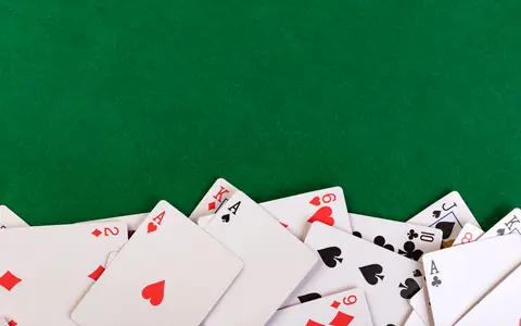 Playing cards scattered on a green felt table, illustrating how to play PPPoker
