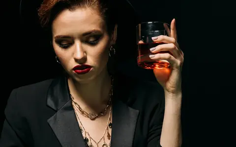 Woman in a hat holding a drink at a poker table, illustrating PPPoker agents