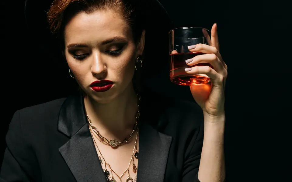 Woman in a hat holding a drink at a poker table, illustrating PPPoker agents