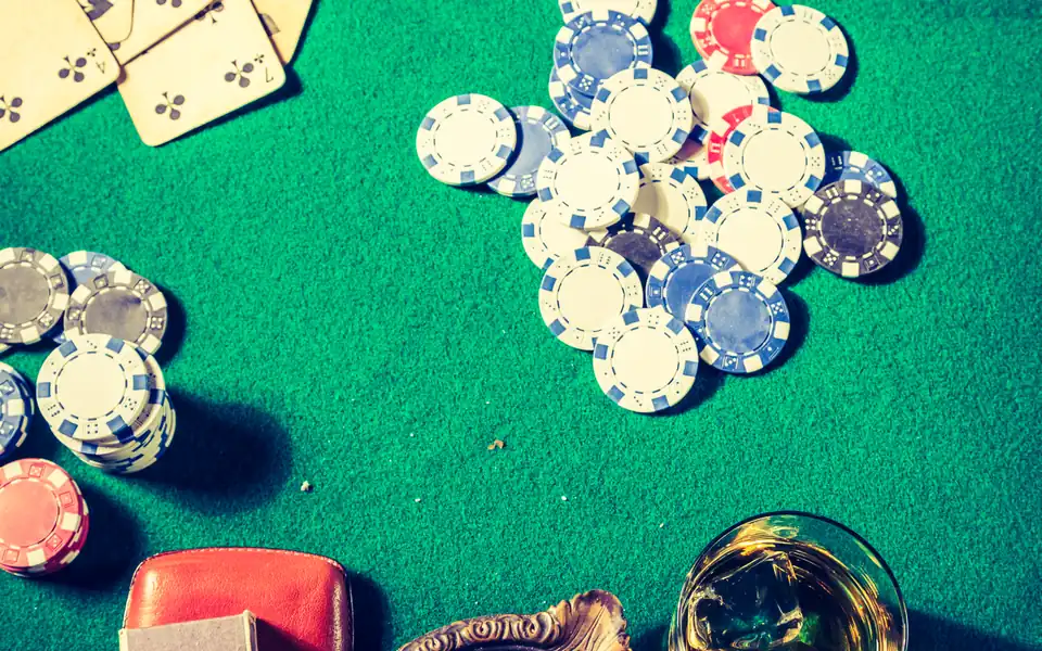 Cards, chips and a drink on a poker table, illustrating poker software and HUD rules