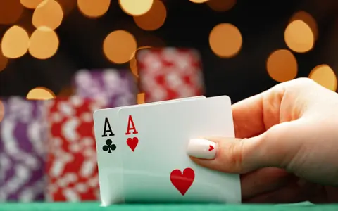 Hand holding two aces in front of poker chips, for the PPPoker login and registration guide