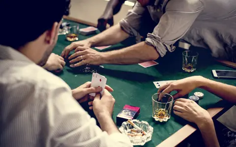 Men playing cards at a table, illustrating a comparison of poker apps for Filipino players